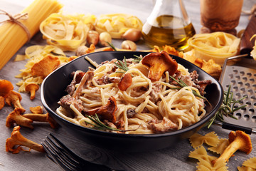 pasta with organic chanterelles. portion of spaghetti pasta with fried chanterelles in a creamy garlic sauce with cheese on a table