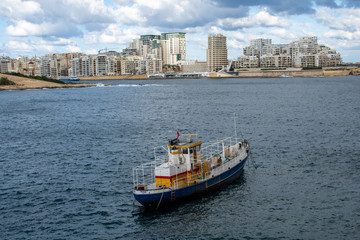 A boat moored in Marsamxett Harbour with Sliema in the background.