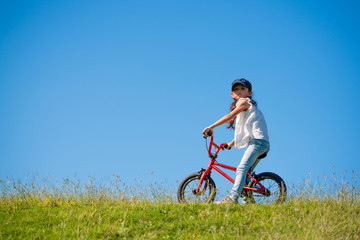 Fototapeta premium 草原で自転車に乗る女の子