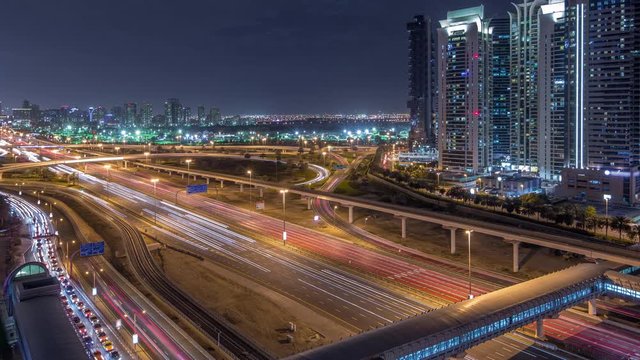 Aerial top view to Sheikh Zayed road surrounded Dubai Marina and JLT skyscrapers night timelapse, Dubai. Traffic, bridges and metro line. United Arab Emirates