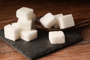 Sugar cubes with wooden spoon. Unhealthy eating concept