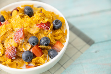 Close up Healthy breakfast.fruit, strawberry, blueberries and cereal with milk in bowl on mat and wooden table. Background Healthy food.