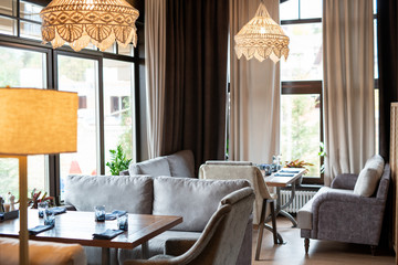 Interior of luxurious restaurant with soft grey velvet couches and wooden tables