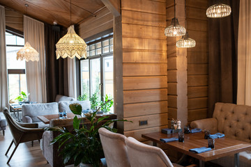 Corner of modern luxurious restaurant with wooden tables served for guests