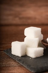 Sugar cubes with wooden spoon. Unhealthy eating concept