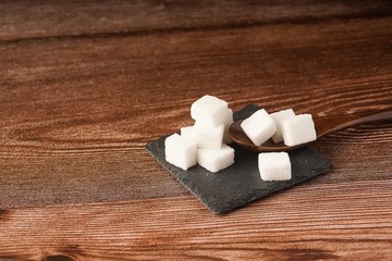 Fototapeta na wymiar Sugar cubes with wooden spoon. Unhealthy eating concept