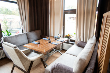 Corner of cozy cafe with comfortable couches and armchair around served table