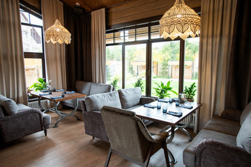 Decorative chandeliers hanging on ceiling above served tables and soft couches