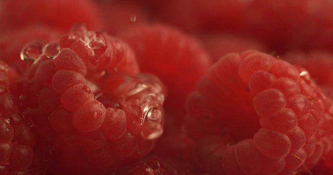 Water dripping onto raspberry in super slow motion