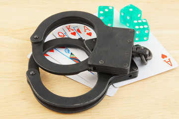 Obraz premium Cards, dices and handcuffs on wooden table, law and gambling concept