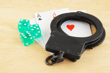 Cards, dices and handcuffs on wooden table, law and gambling concept