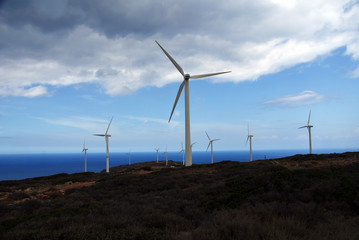 wind power plants on a mountain against a background of blue sky and sea