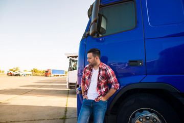 Portrait of professional truck driver standing by his truck vehicle. Transportation service.