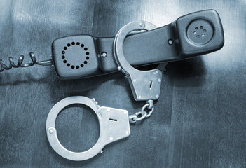 Obraz premium Telephone reciever with handcuffs close up