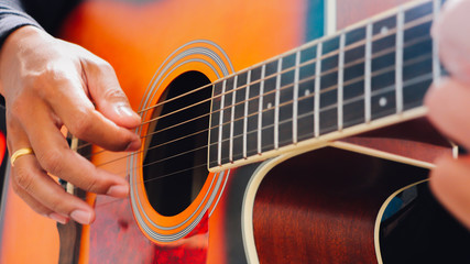 Man's hand playing acoustic guitar, close up