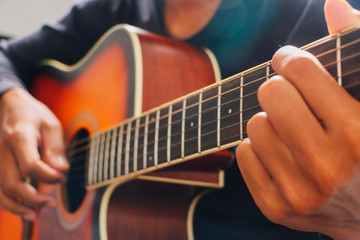Man's hand playing acoustic guitar, close up