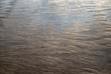 blue clear sky reflected in very wet embossed sand at low tide