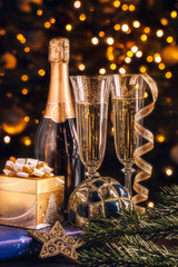 New Year composition. Bottle of champagne with decoration in front of Christmas tree