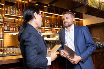 Two owners of luxurious restaurant interacting by bar counter