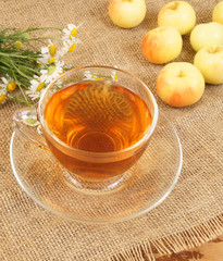 Herbal tea and small apples on burlap background