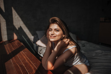 Girl sitting on the bed by the window in the sunlight