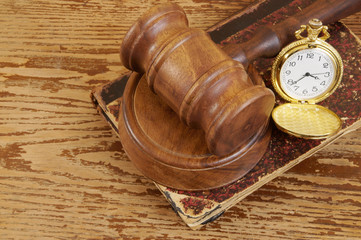 Judge's gavel, legal book and watch on old wooden background