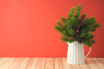 Christmas holiday celebration concept with pine tree branches in vase on wooden table.