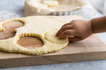 Baby's hands makes traditional cookies. Raw dough and clippers in the form of symbols for the holiday cookies on the table. Christmas. New year