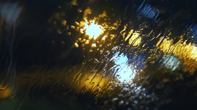 Rain dropping on a windshield at night, wipers on, 4K