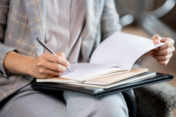 Young school teacher with pen correcting mistakes or putting mark in copybook