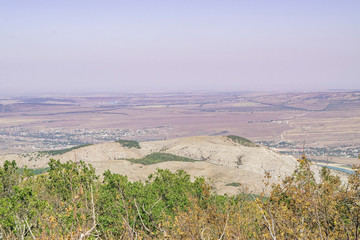 Crimean landscape, oak grove and mountains Karadag in the distance covered with fog. Crimea, Russia.
