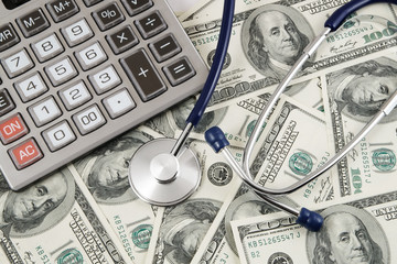 Calculator and stethoscope on banknotes background, cost of healthcare concept 