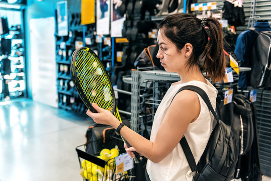 girl chooses a tennis racket in a supermarket