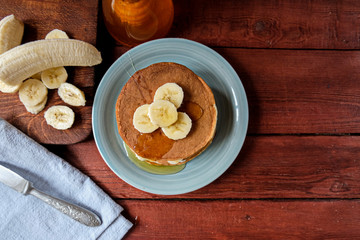 Home-made banana pancake on a blue plate. Eat with maple syrup or honey and fresh fruit. The concept of healthy homemade food. Copy space