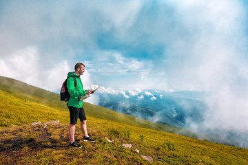 tourist with backpack and map in mountains