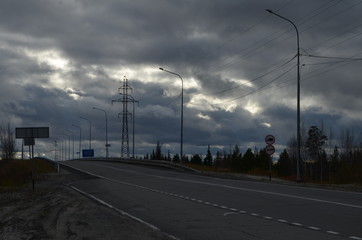 The road out of town into the distance, against the sky and clouds.