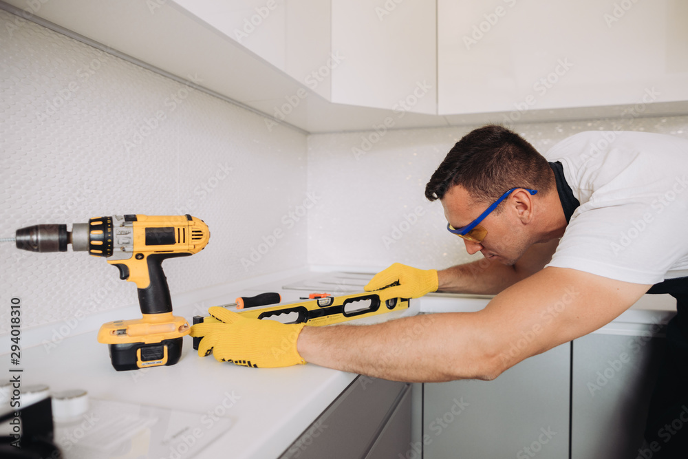 Wall mural Maintenance man installing kitchen furniture