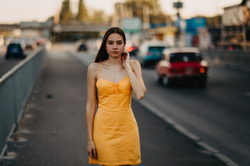 A young woman walks on the sidewalk at the street.