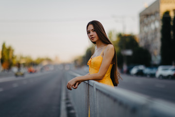 A young woman stands on a background of cityscape.