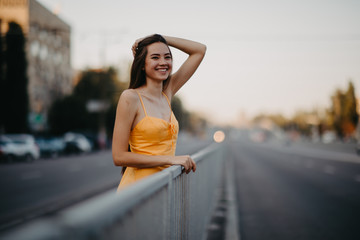 A young woman stands on a background of cityscape.
