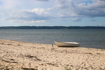 Small white boat at the beach near the lake
