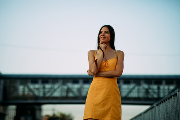 Woman stands on a background of a bridge and sky.