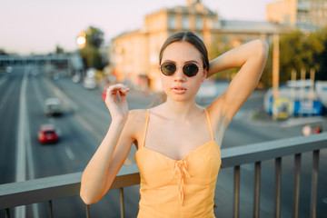 Woman stands on the bridge above the road on a background of cityscape.