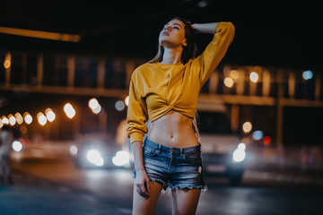 A young woman walks in the night city.