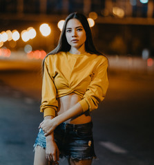 A young woman walks in the night city.