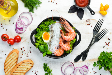 Rice noodles with shrimps, egg and herbs in a black plate on a white wooden background. Top view. Free space for your text.