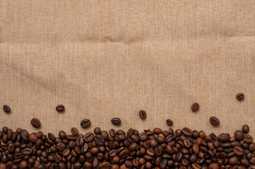 Background with fresh roasted coffee beans on a jute cloth, lot of copy space