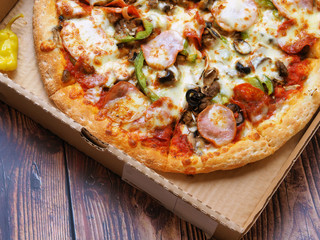 Pizza with meat, cheese and olives in a cardboard box