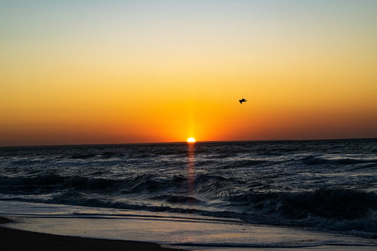 Sunrise over the Black sea, waves on the sandy beach.