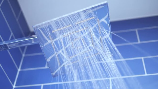 Opening shower stream in a bathroom, blue tiles background, close up, 4K